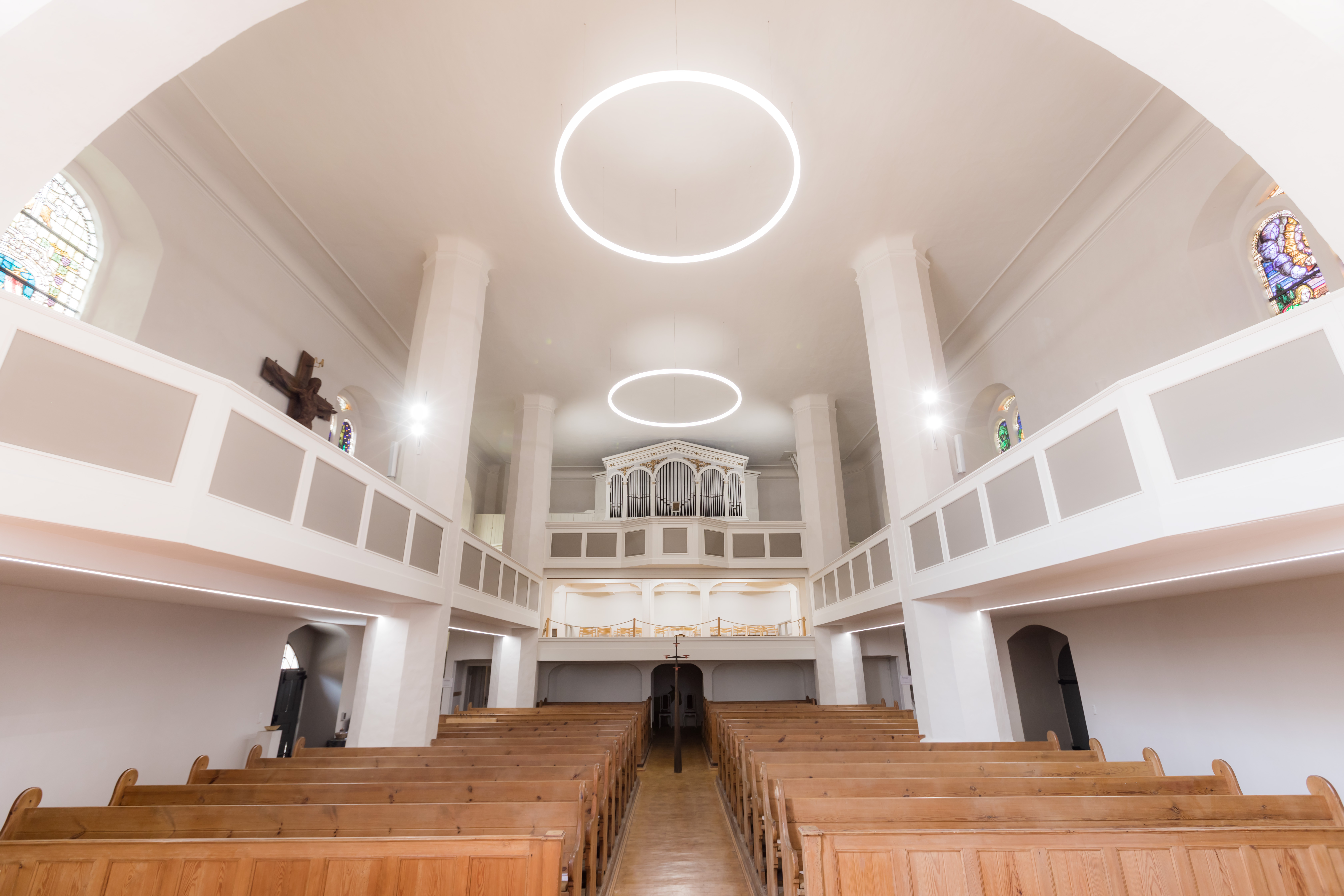 Ringleuchte TheO im Hauptschiff einer Kirche mit warmer Beleuchtung