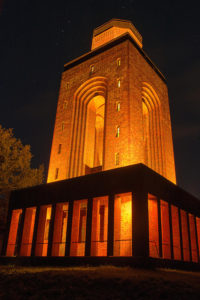Bild des in gelb-orange beleuchteten Bismarckturms bei Nacht
