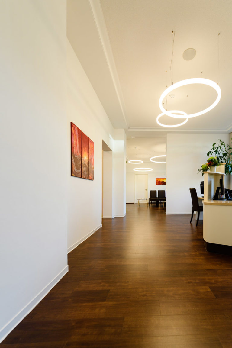 Flur Augenklinik Dr. Stoll mit Bildern an der Wand und Lampen an Decke