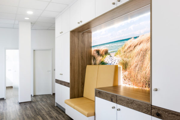 Flur Zahnarztpraxis mit Wartebereich mit LED Deckenleuchten und hinterleuchtetem Bild vor Sitzbank