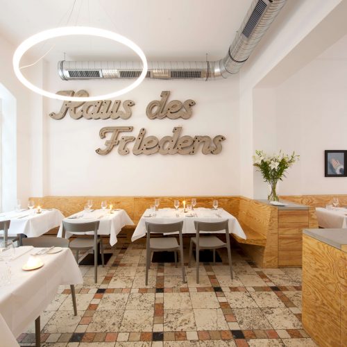 Restaurant-Ross Berlin mit Schriftzug Haus des Friedens und Designer Ringleuchte TheO