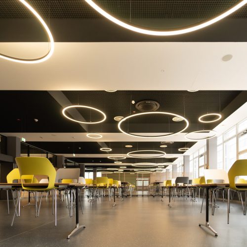 Sitzbereich der Mensa der BTU Cottbus mit LED-Ringleuchten TheO Black und dunkler Decke.
