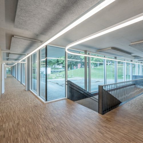 Langer verglaster Flur mit kontinuierlicher LED-Lichtlinie an der Decke